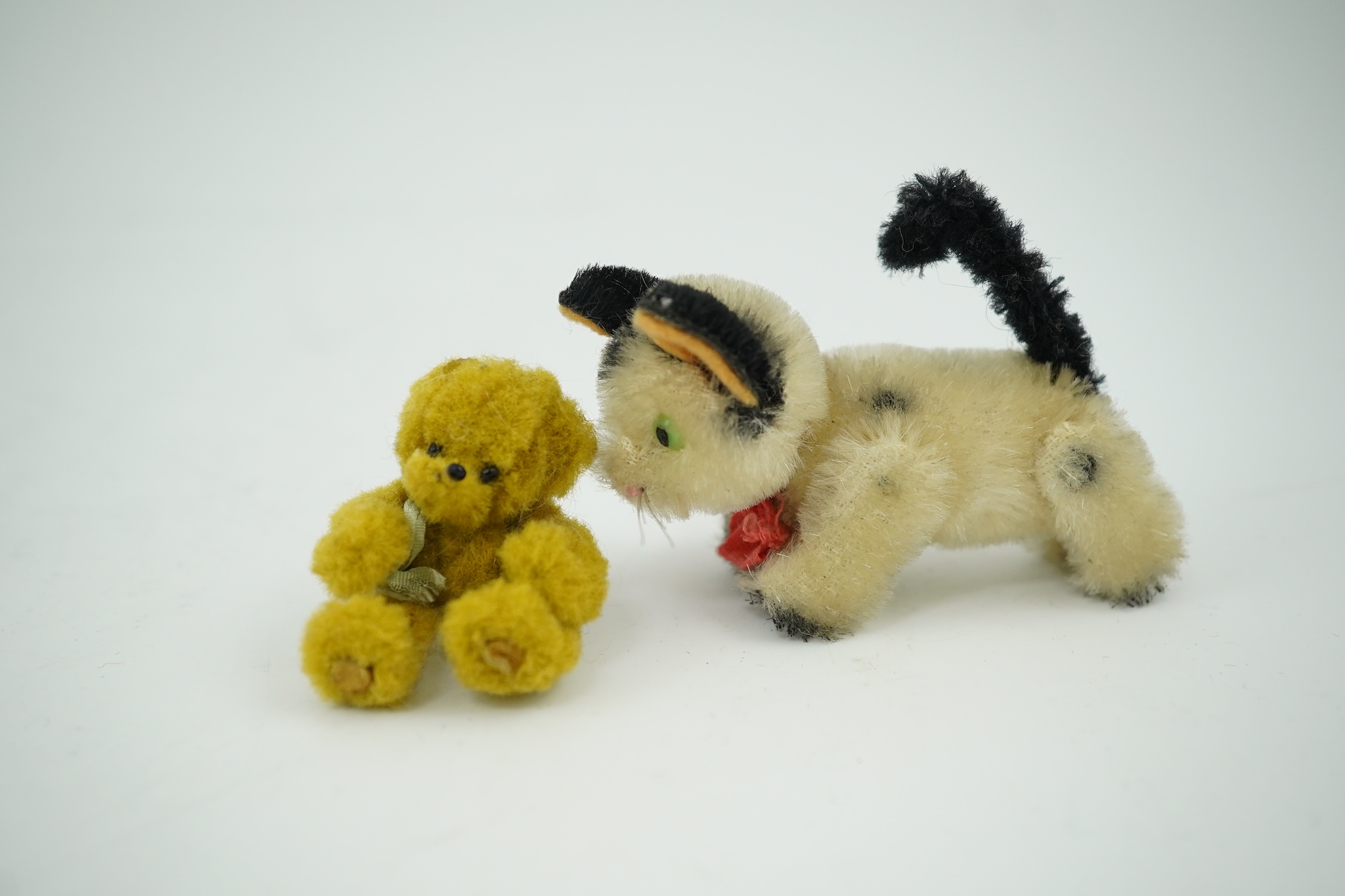 A small Schuco cat with revolving head and a tiny jointed teddy bear, largest 9cm in length. Condition - fair to good